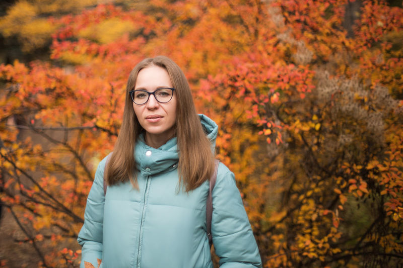 Portrait of beautiful woman standing against trees during autumn