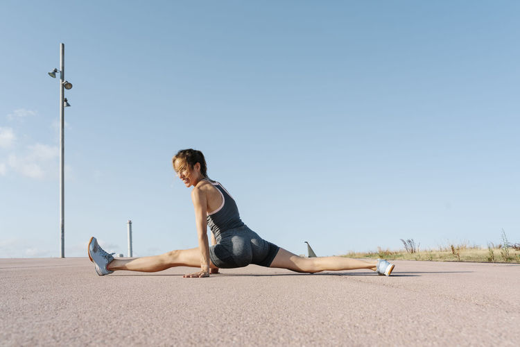 Female sportsperson exercising splits on sunny day