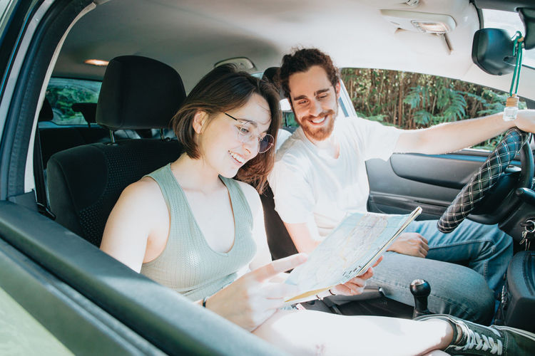 Smiling man and woman looking at map in car