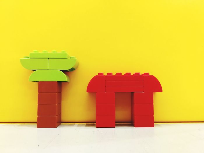 Close-up of plastic toys on floor against yellow wall