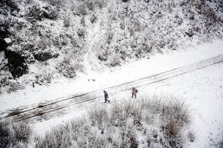 Aerial view of people walking on snow covered road