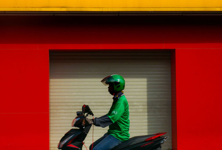 Side view of man riding motorcycle against building