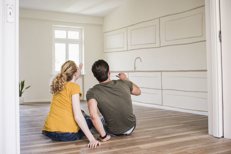 Young couple in new home sitting on floor thinking about interior design