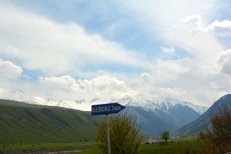 Road sign on landscape against sky