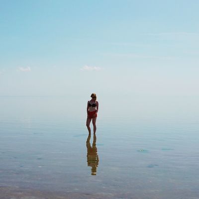 Young woman standing amidst sea against sky