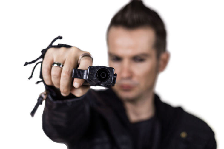 Portrait of young man photographing against white background