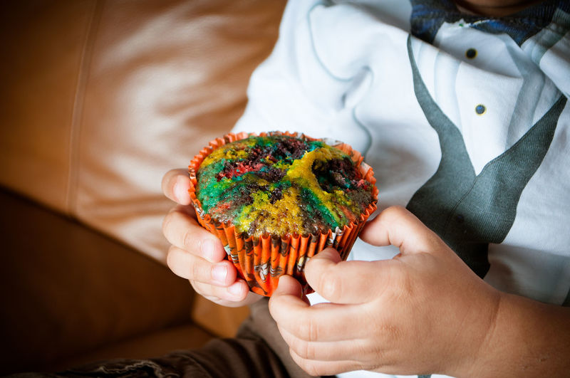 Midsection of boy holding cupcake at home
