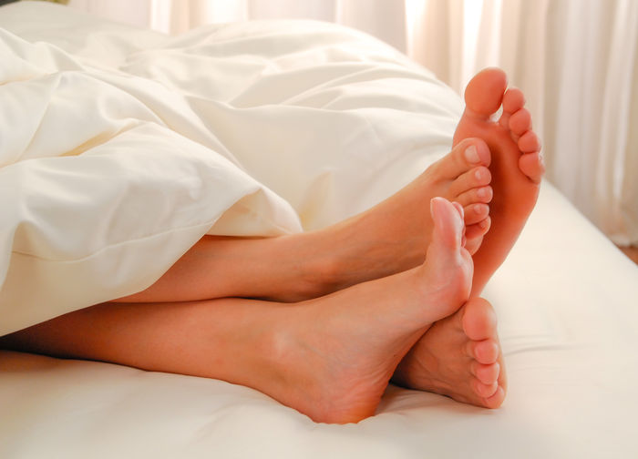 Low section of woman relaxing on bed