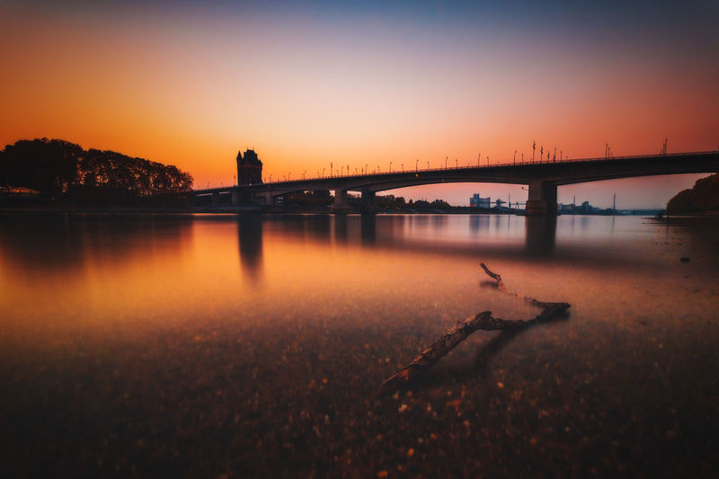 Bridge over river against sky during sunset