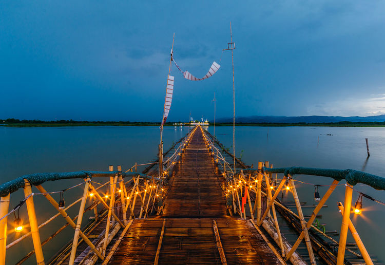 Empty pier over river against sky