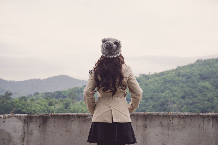Rear view of woman wearing warm clothing looking at mountains
