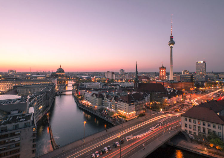 Illuminated buildings in city against sky during sunset