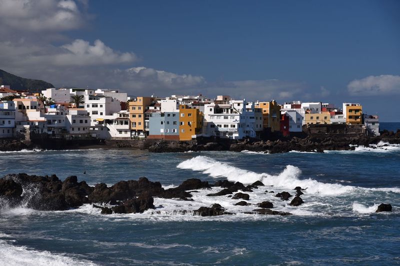 Sea by buildings against sky in city