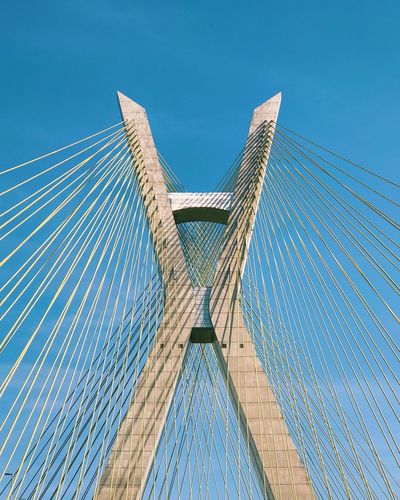 Low angle view of suspension bridge against blue sky