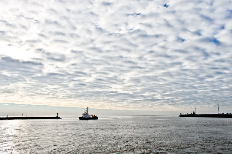 Ship in sea against cloudy sky