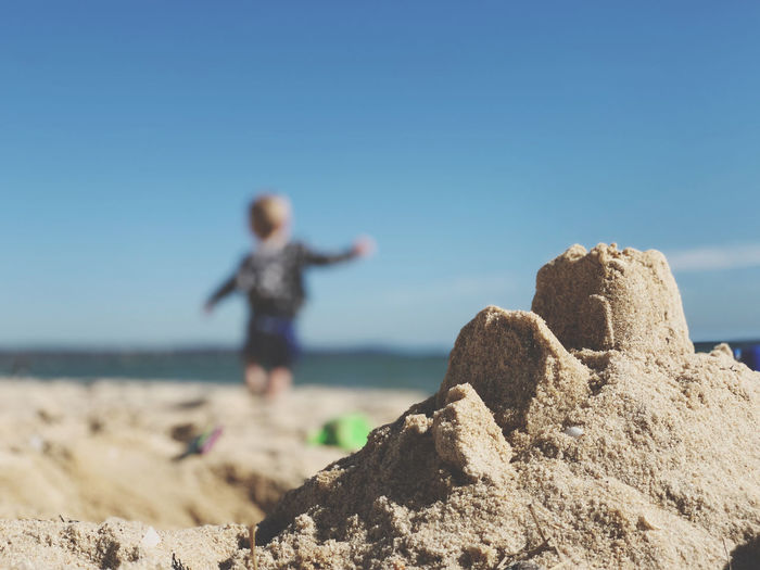 Close-up of sandcastle with boy in background