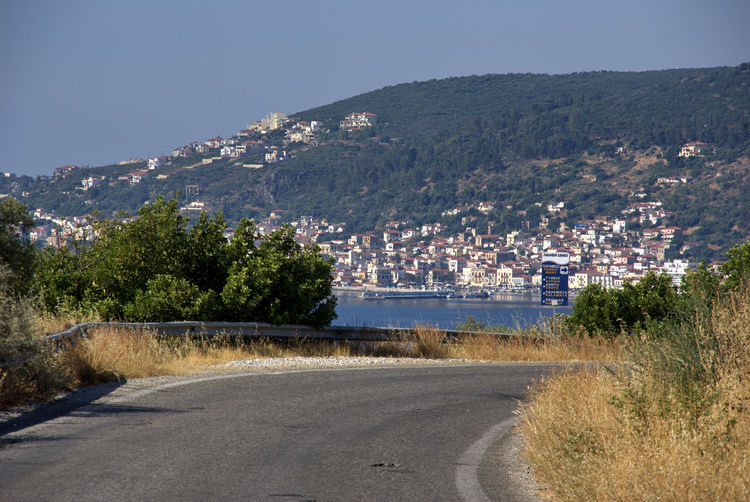 Road by buildings in city against sky