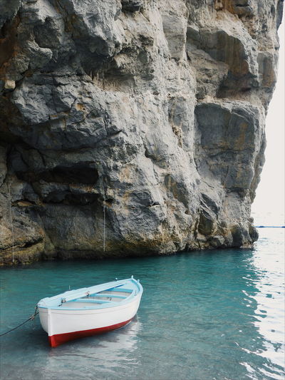 Boat on sea by cliff