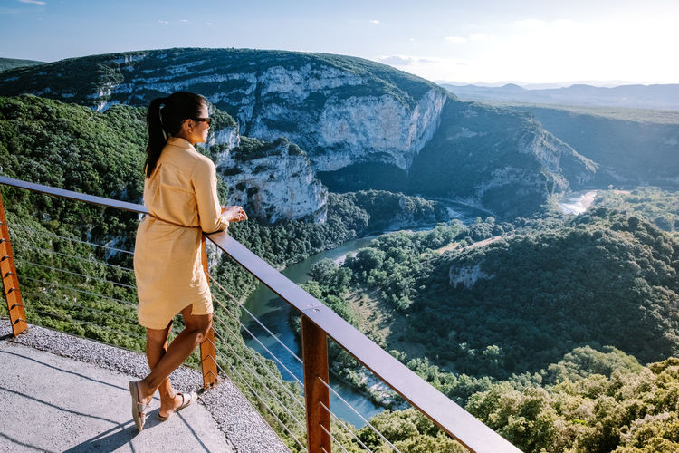 Woman standing on railing against mountain