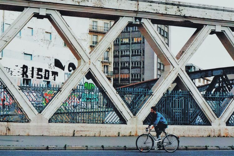 Man riding bicycle on bridge in city