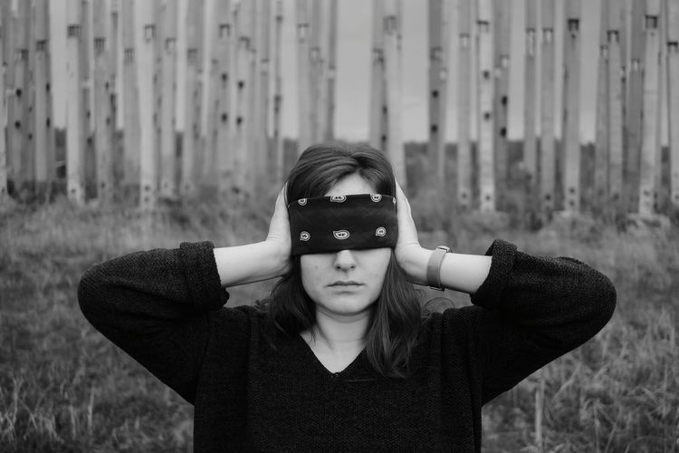 Young woman with blindfold standing outdoors