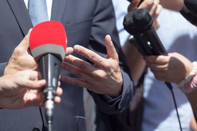 Close-up of reporters with microphone taking interview of businessman