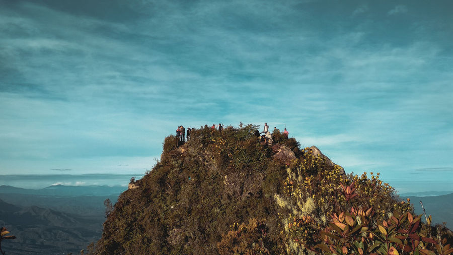 Group of people on rock against sky
