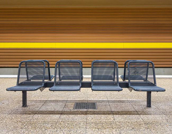 Empty bench against yellow wall