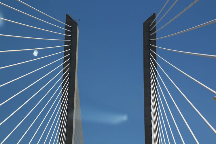 Low angle view of bridge cables against blue sky