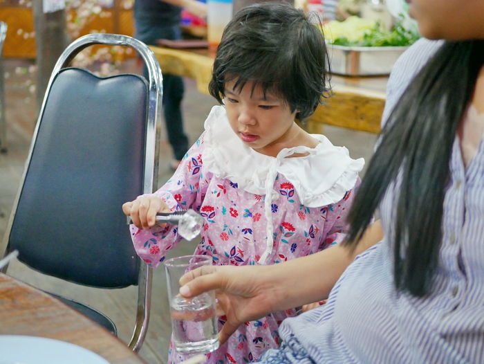 Cute girl putting ice cube in glass of water
