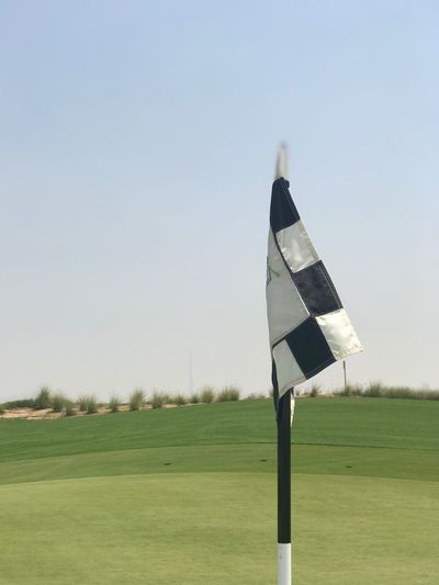 Flag on golf field against clear sky