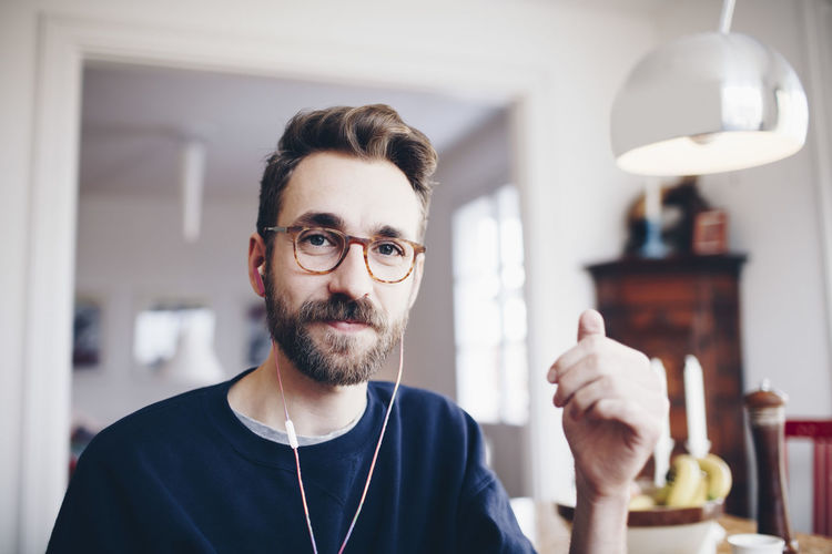 Portrait of happy man listening to music in headphones at home