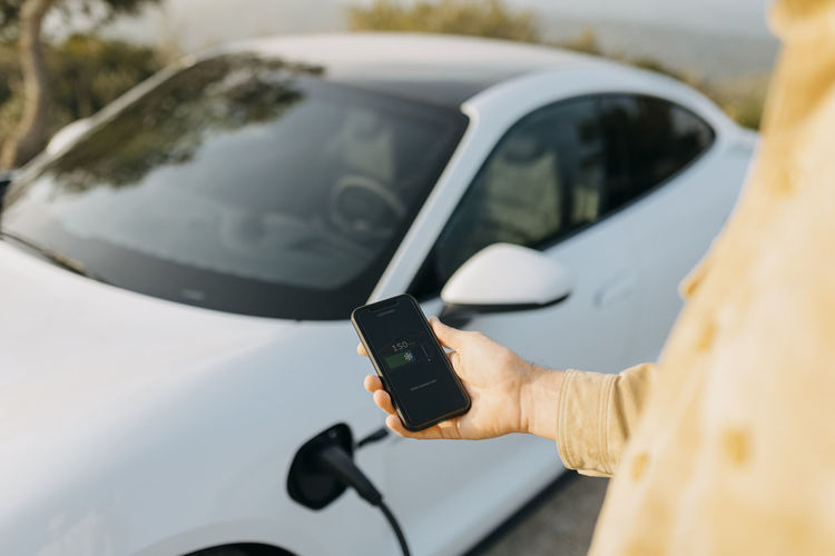 Man checking battery level of electric car on smart phone