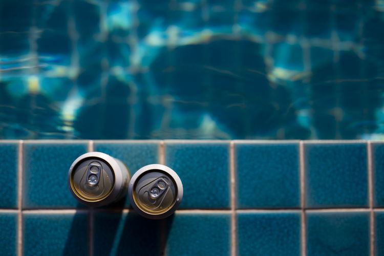 Selective focus two white beer cans are placed at the edge of the pool with space for text 