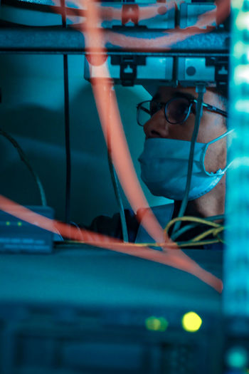 An computer science enegeneer work on his network picture took behind cables and wires 