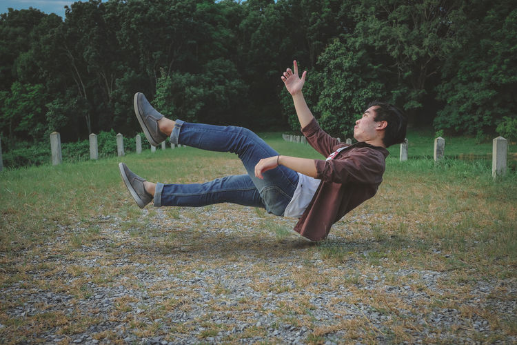 Side view of young man levitating over land