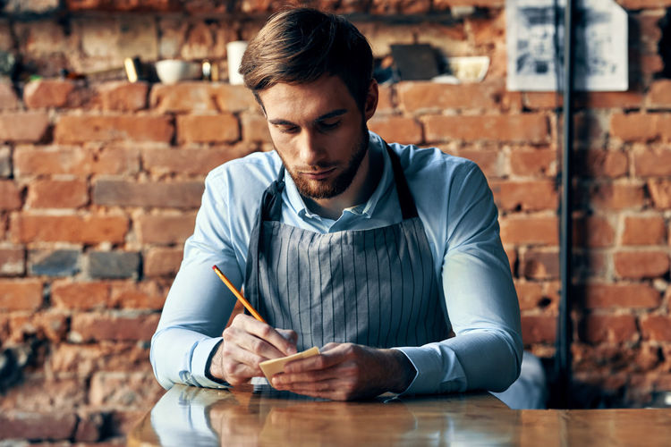 Young man looking away while sitting on table