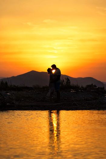 Rear view of silhouette couple kissing at sunset