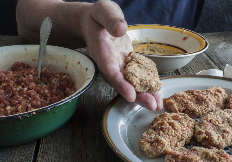 Cropped image of hands mixing batter by minced meat at table