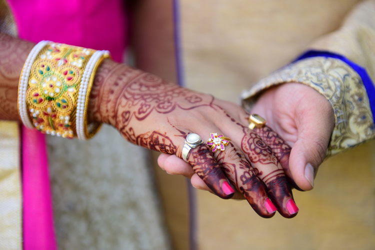 Midsection of bridegroom holding bride hand