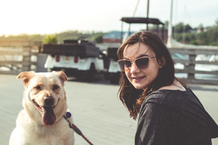 Portrait of smiling young woman holding dog at beach