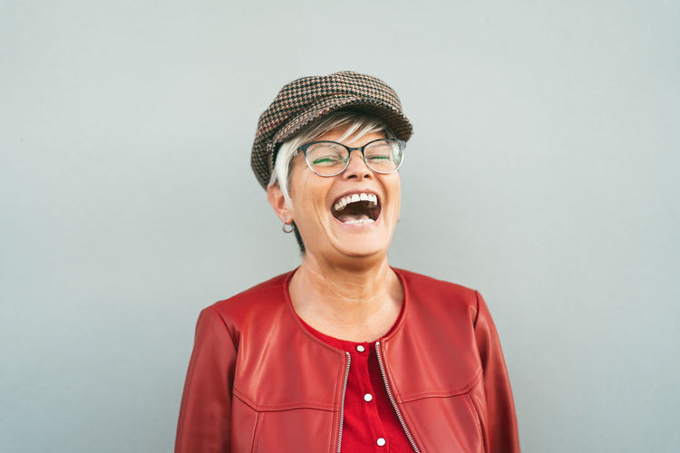 Woman laughing while standing against gray background