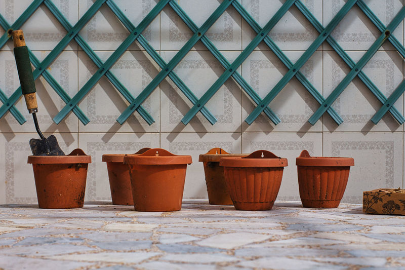 Flower pots on a marble table with a pergola on the background wall.mini shovel in a pot.