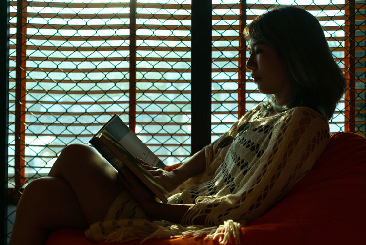 Woman reading book while sitting at home