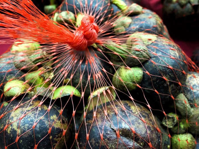 Close-up of mangosteens in net at market stall