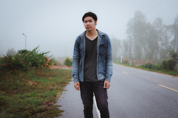Portrait of young man standing on road