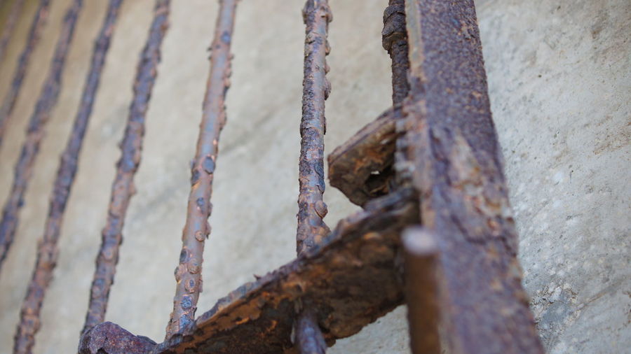 Low angle view of rusty metallic gate against wall