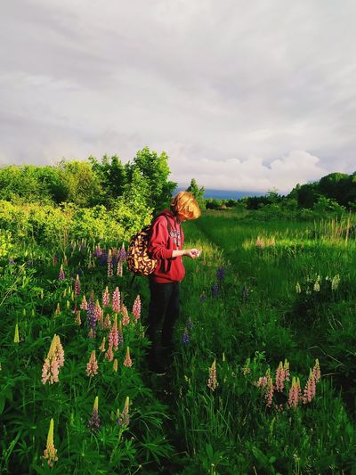 Boy standing on grassy land against sky
