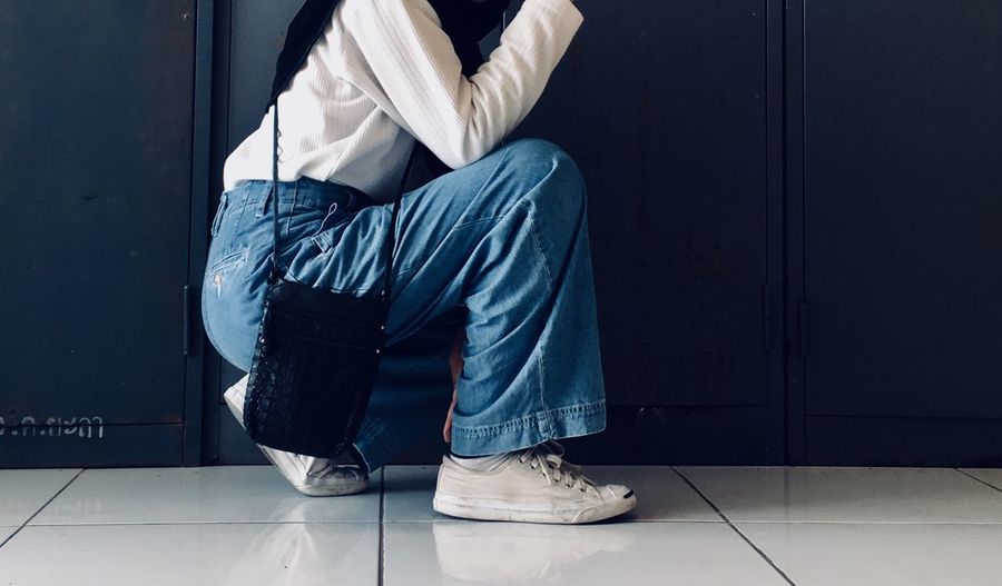 Low section of woman crouching on tiled floor