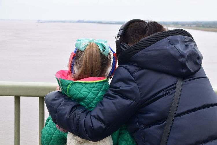 Rear view of mother and daughter in warm clothing looking at view